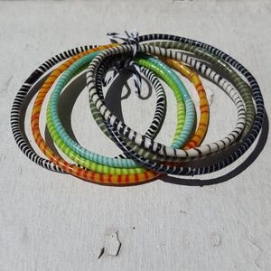 Set of 7 multi-colored striped bracelets.